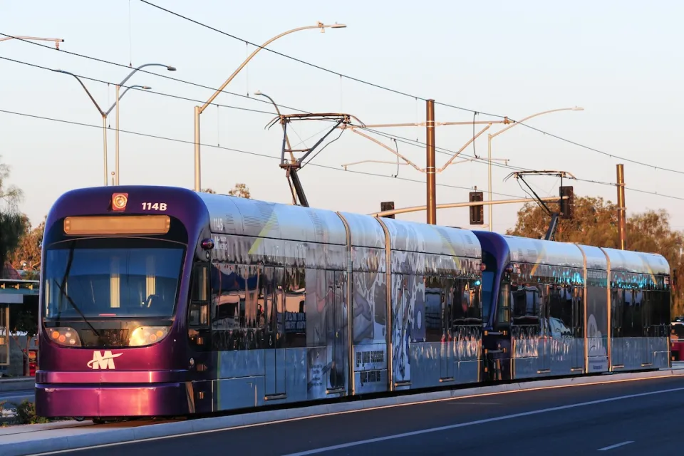 Purple Phoenix light rail train on rail at golden hour.